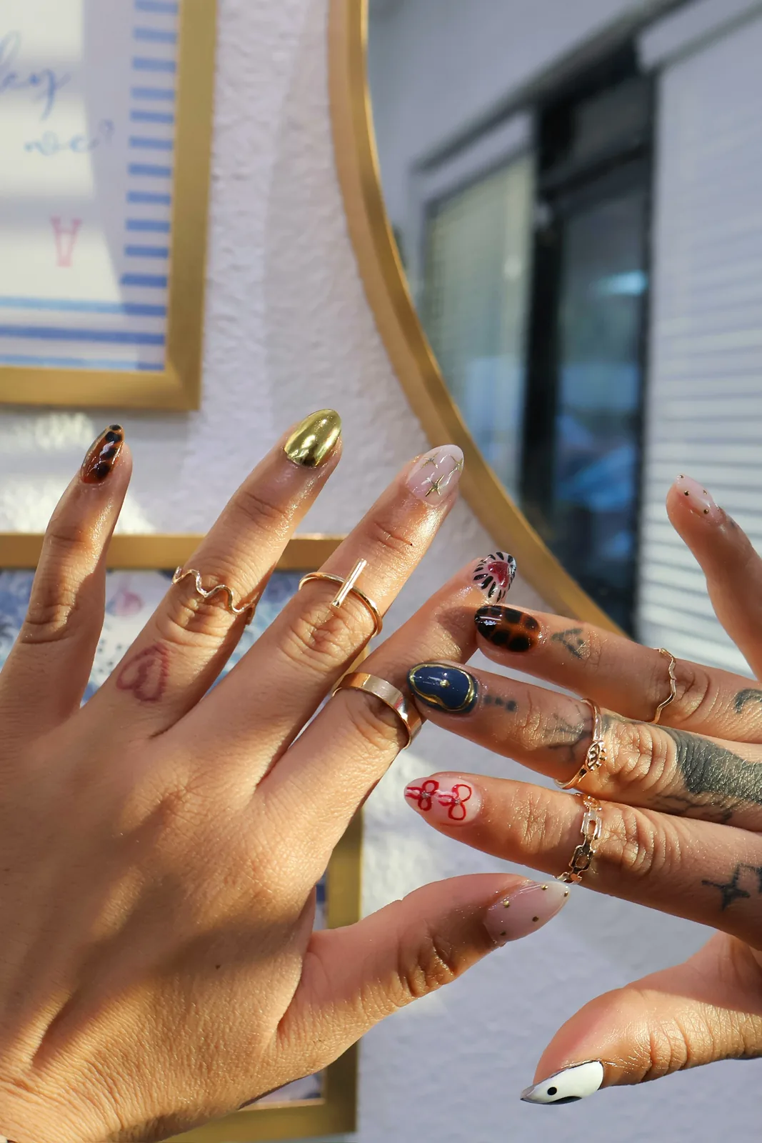 Eclectic chrome and tortoiseshell nail art shown beside a gold mirror