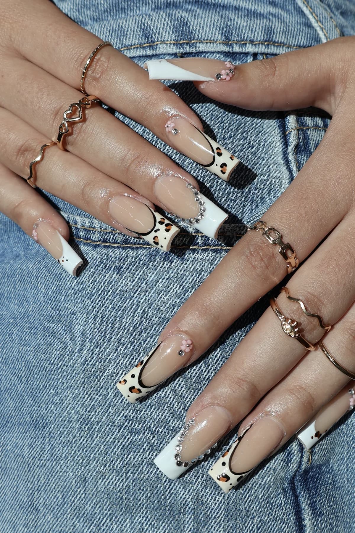 White leopard-print French nails with scattered rhinestones on denim
