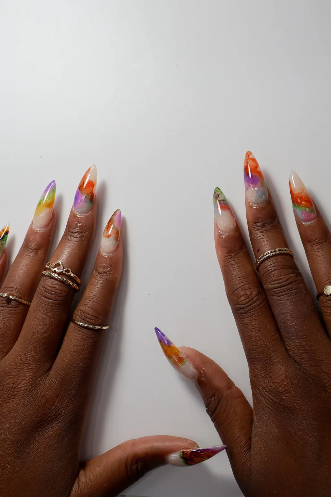 Both hands displaying hand-painted watercolor stiletto nail art